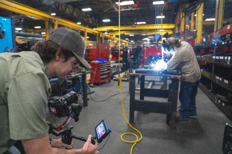 Filming a welder at the bench inside a manufacturing plant