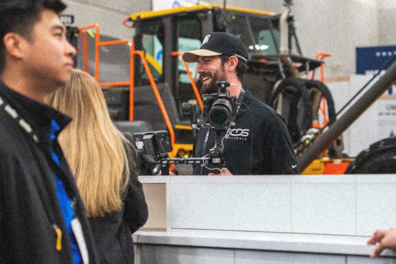 Filming an interview beside the machines on the World of Asphalt floor