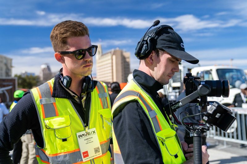 Two crew in high-vis and headsets running camera at the outdoor demo