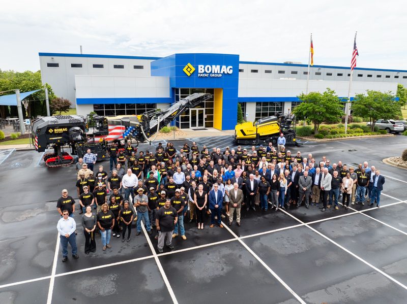 Aerial of the whole company posed outside the BOMAG building, machines flanking the group