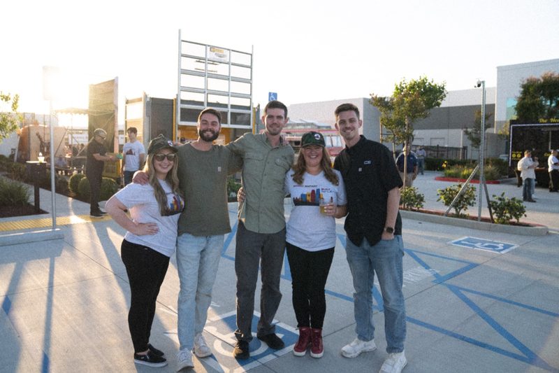 The crew together on the plaza after the shoot, scaffold rising behind them