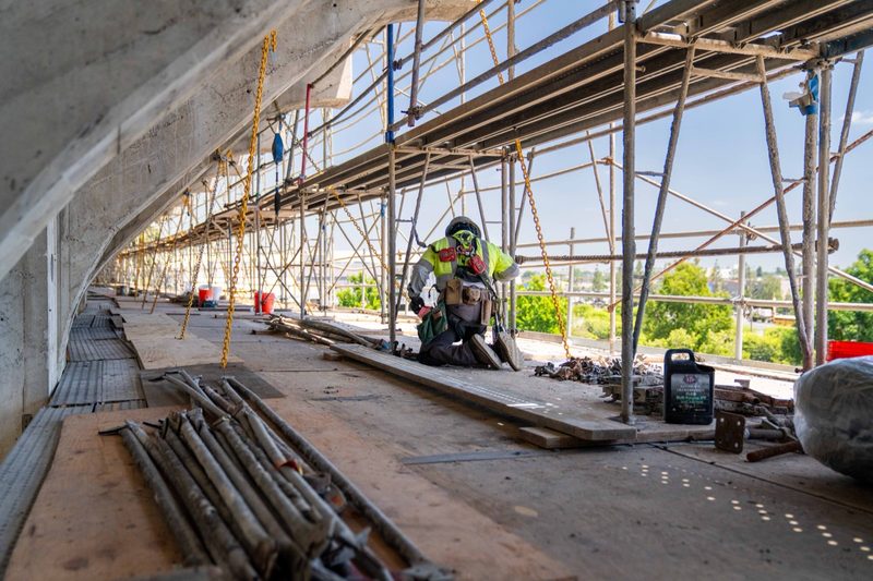 A worker on the scaffold run threaded along the underside of the deck