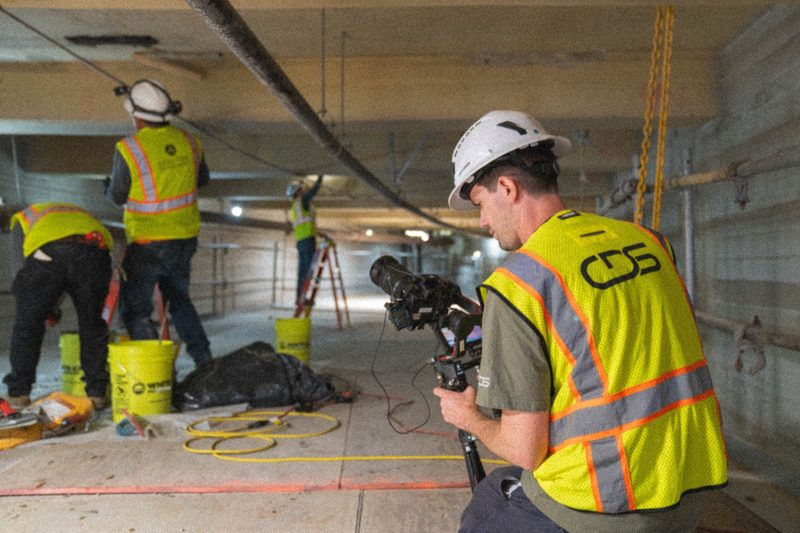 A shooter filming inside the concrete undercroft while work goes on behind