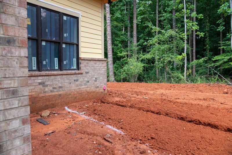 The finished corner in brick and siding, black windows above fresh red clay