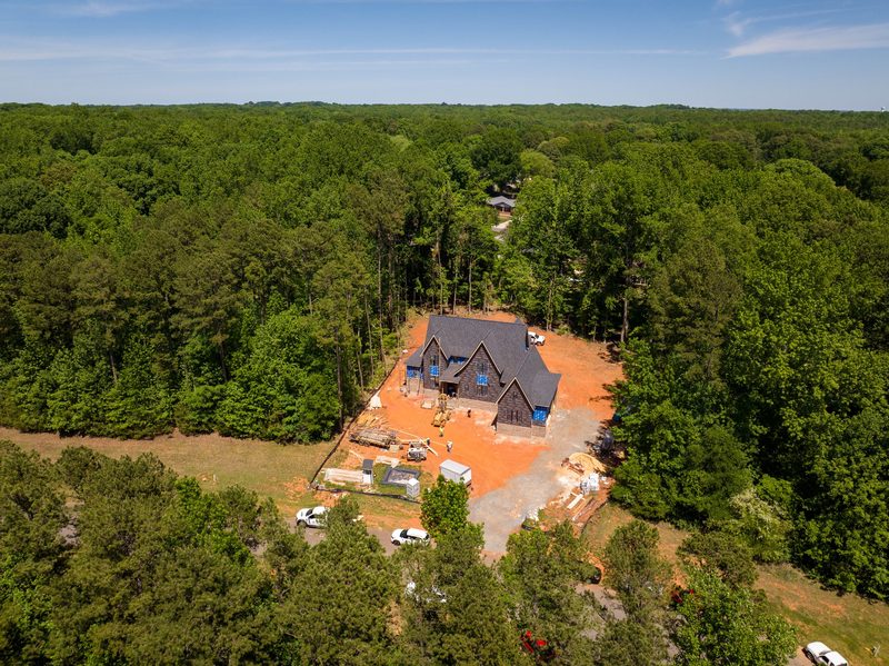 Aerial of the roofed house in its clearing, woods closing in on every side