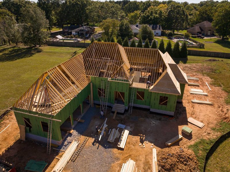 Aerial of the house at sheathing stage, green wrap on and the neighbourhood beyond