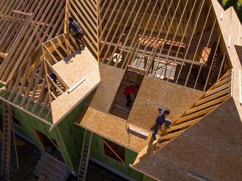 Aerial down into the open second floor, two carpenters working the deck