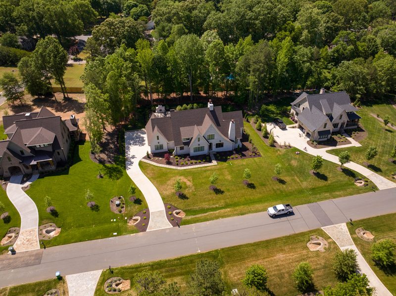 Aerial along the street, finished houses set back on their lawns