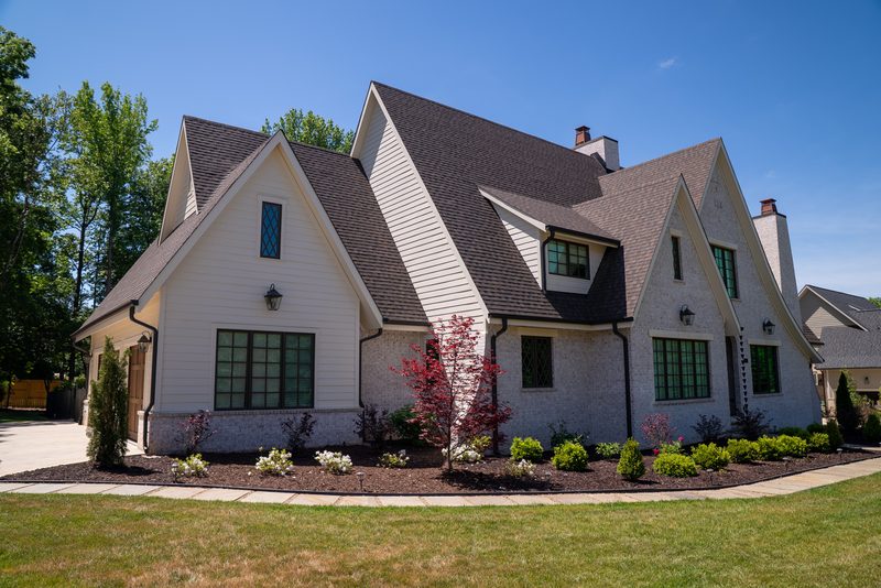 The finished house in white with dark windows, planting beds in