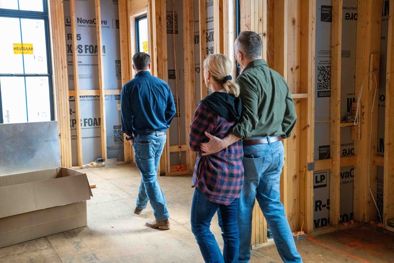 Three people looking out through a window opening in the framed room