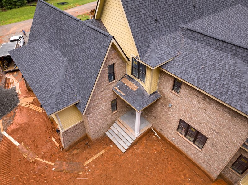 Aerial detail of the finished roofline, brick and siding meeting at the porch