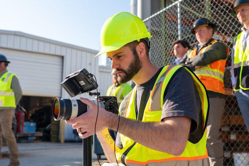 A shooter filming the run in a green hard hat, the crowd waiting behind him