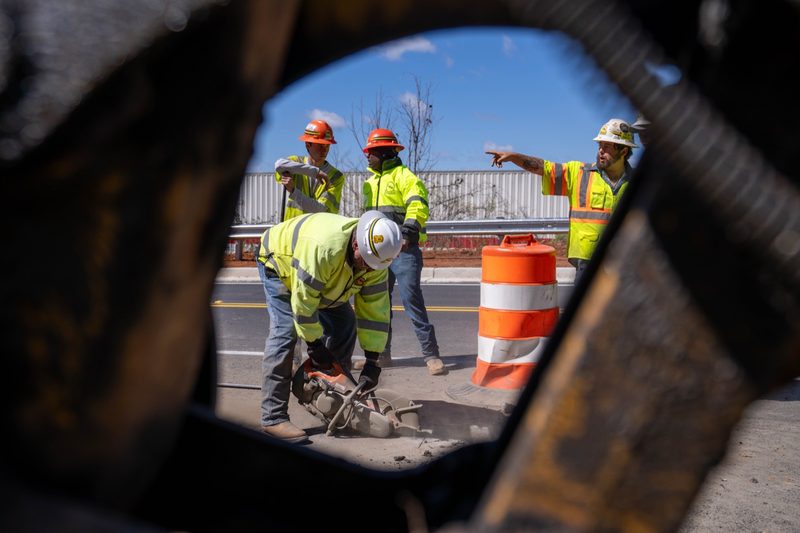 Framed through a machine window, a foreman pointing out the next move
