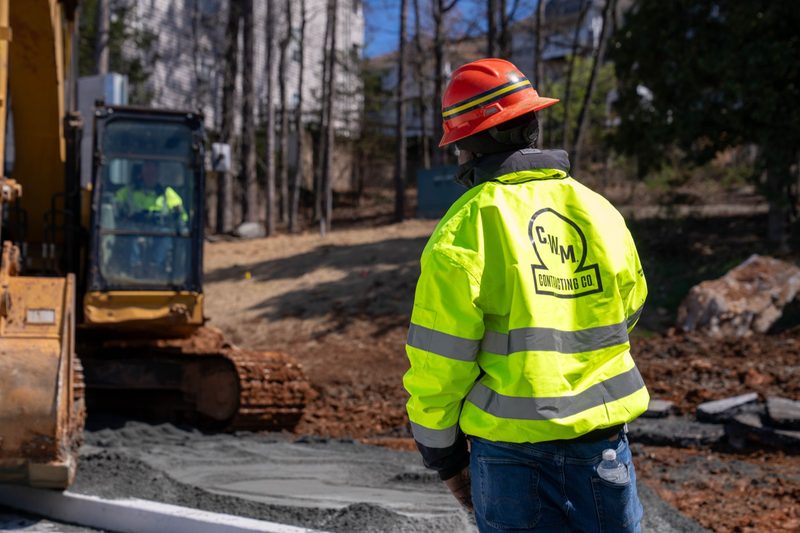 A worker in a C.W. Matthews jacket watching the excavator work