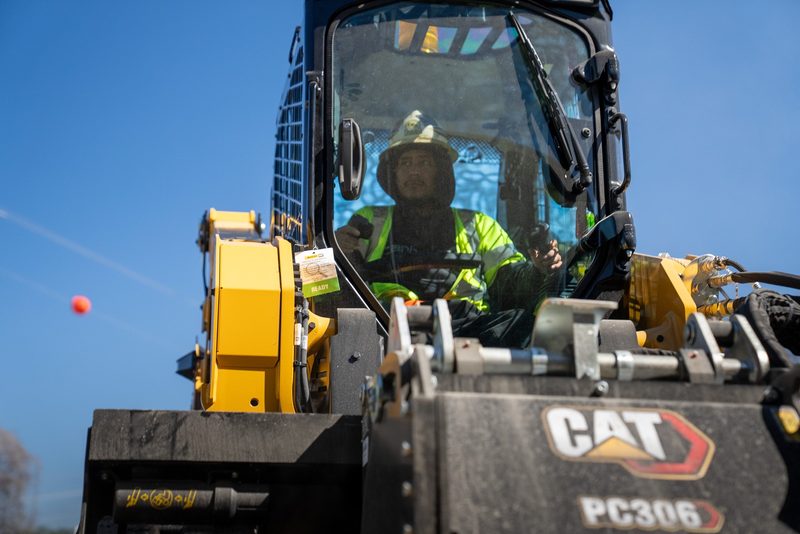 A CAT PC306 cold planer on the skid steer, operator lining up the cut