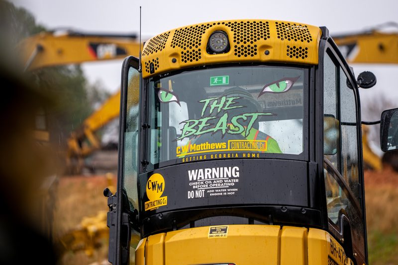 An excavator cab lettered THE BEAST above the C.W. Matthews mark