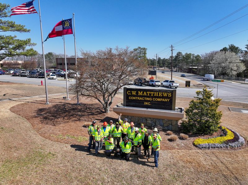 The whole crew gathered at the C.W. Matthews sign under the flags