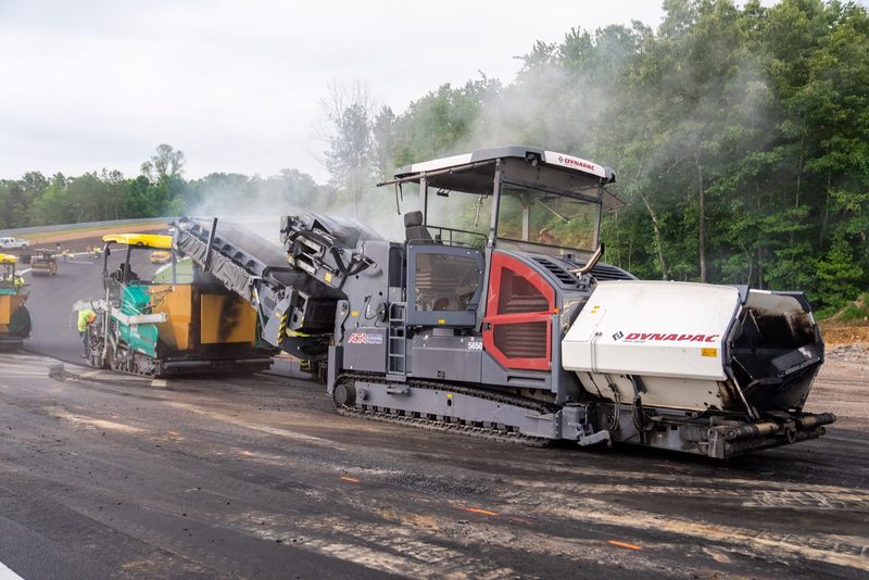 A Dynapac paver laying hot mix, steam rising off the mat