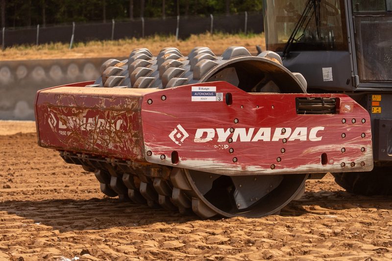 Close on the padfoot drum of a Dynapac soil compactor working red dirt