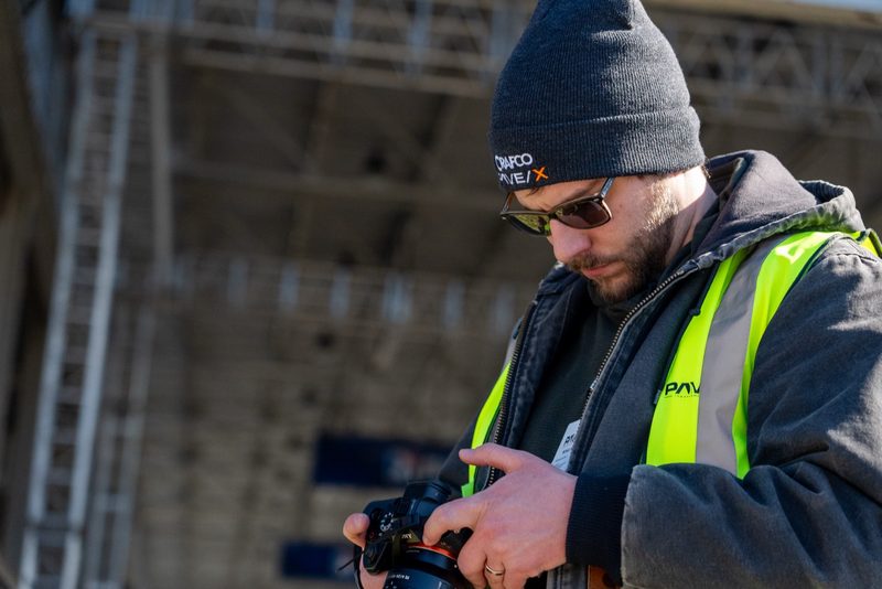 A crew member checking the take on camera, Pave/X beanie pulled down