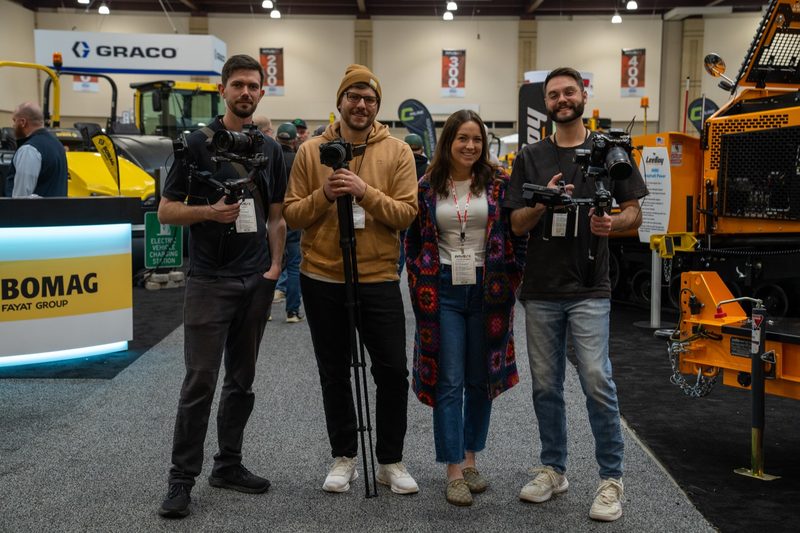 Four of our crew with cameras in front of the BOMAG stand