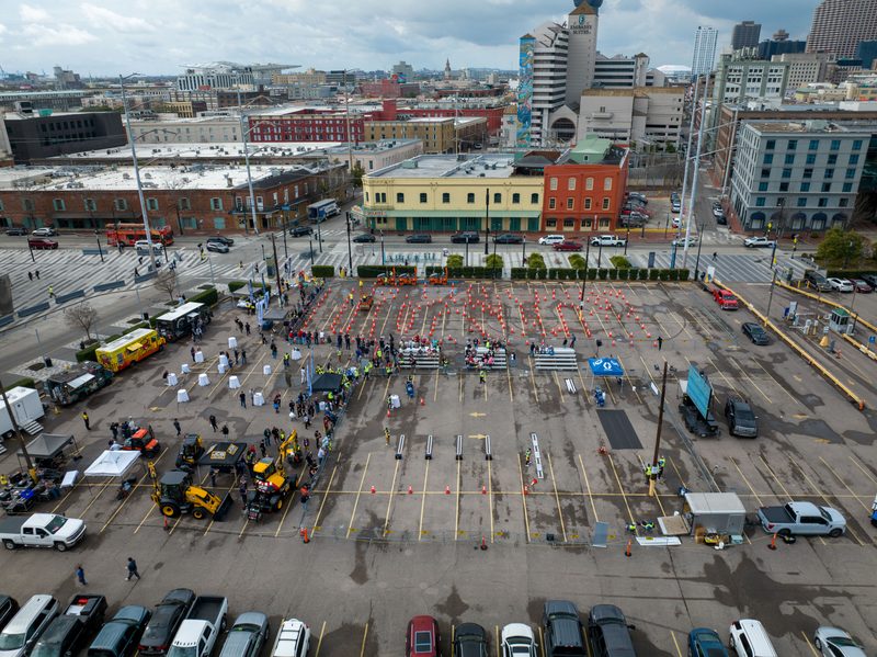 Aerial over the outdoor demo lot, machines and cones laid out against the skyline