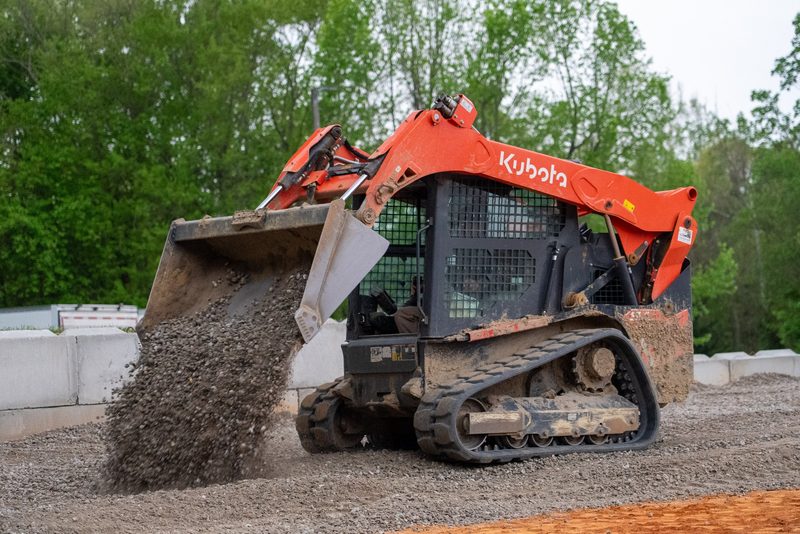 A Kubota track loader spilling gravel out of a raised bucket