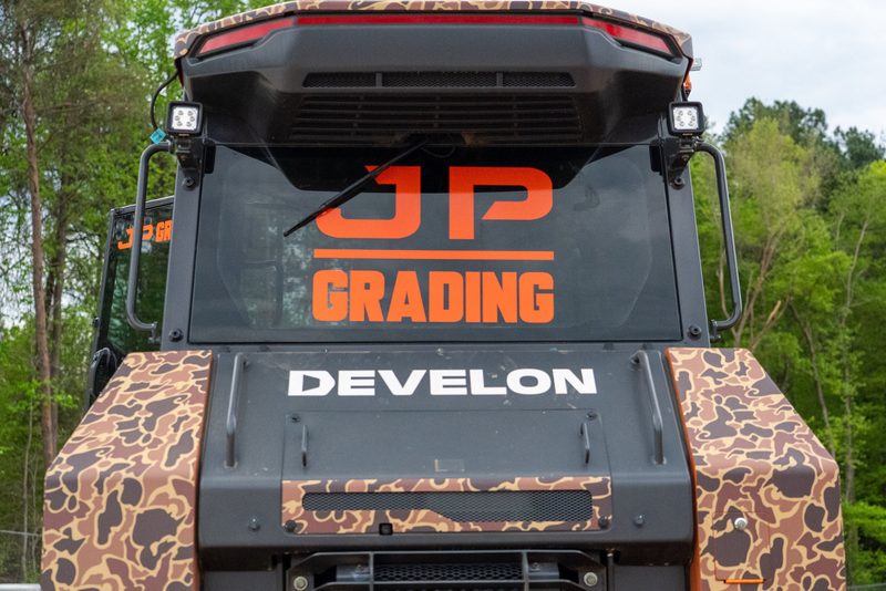The JP Grading name across the canopy of a Develon machine