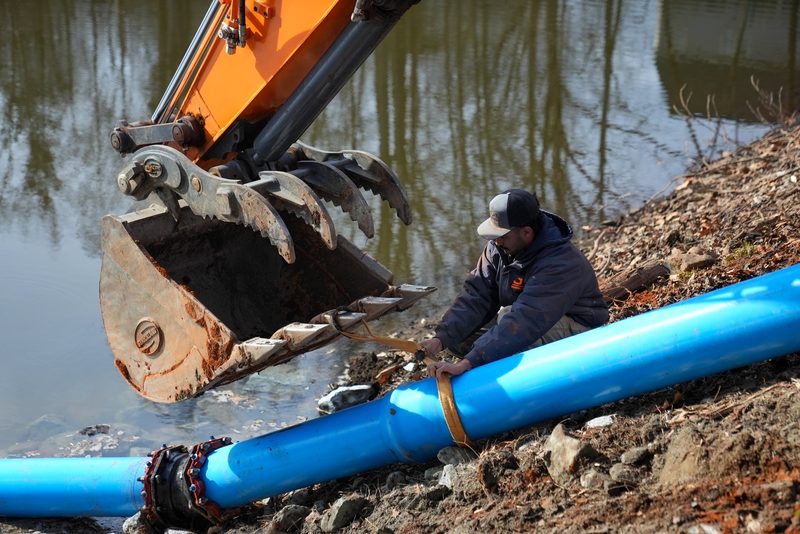 A worker down in the water making up the joint on a blue water main