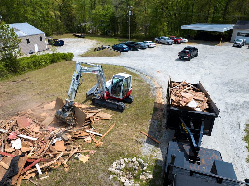 An excavator feeding demolition debris into the dump trailer