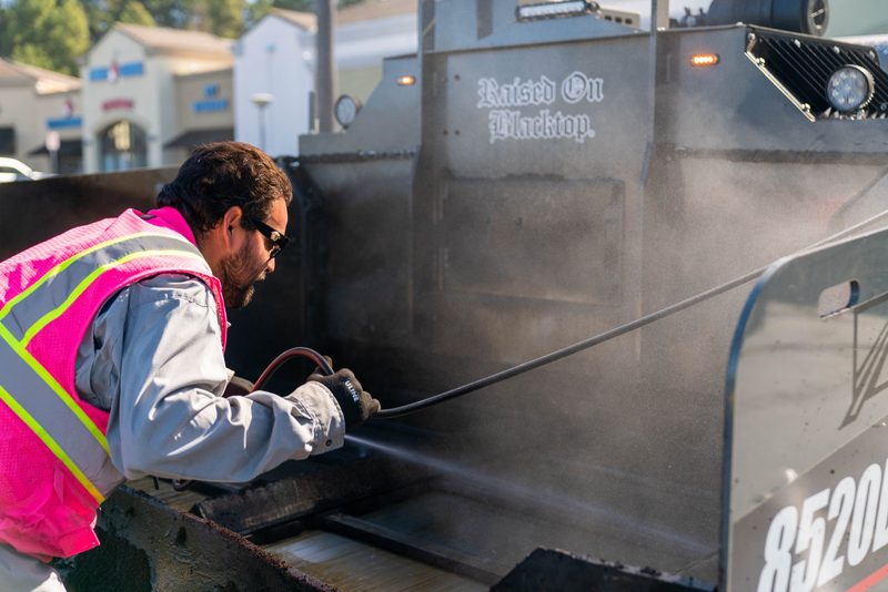 A worker washing down the hopper of an 8520, steam coming off the steel