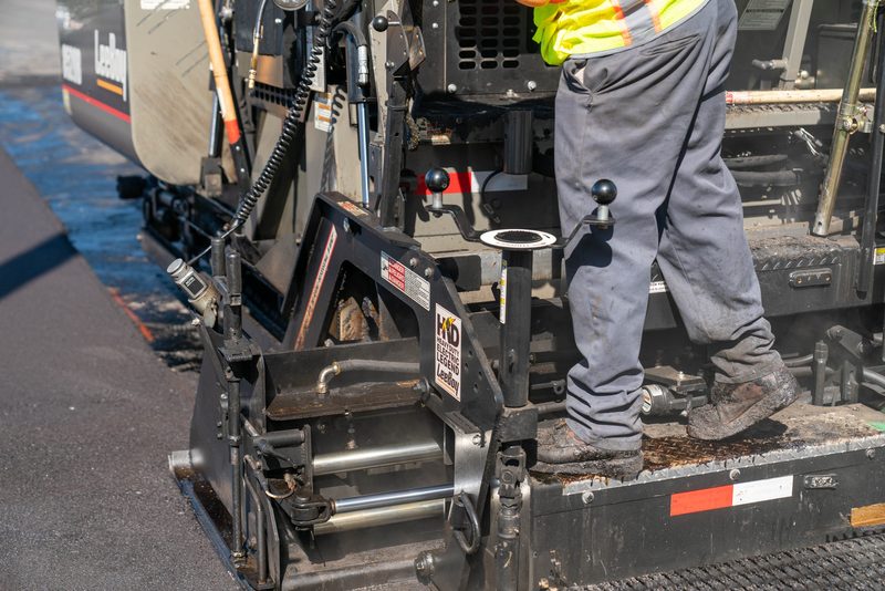 Detail at the screed, a crew member riding the plate