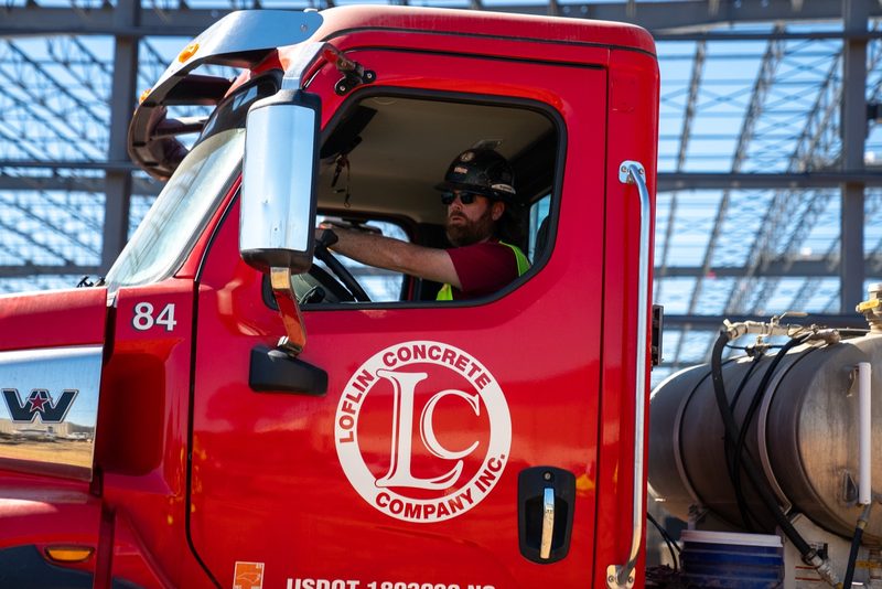 A driver at the wheel of a Loflin mixer, the LC mark on the door