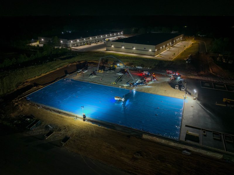 Night aerial of the lit pour, the vapour barrier glowing blue