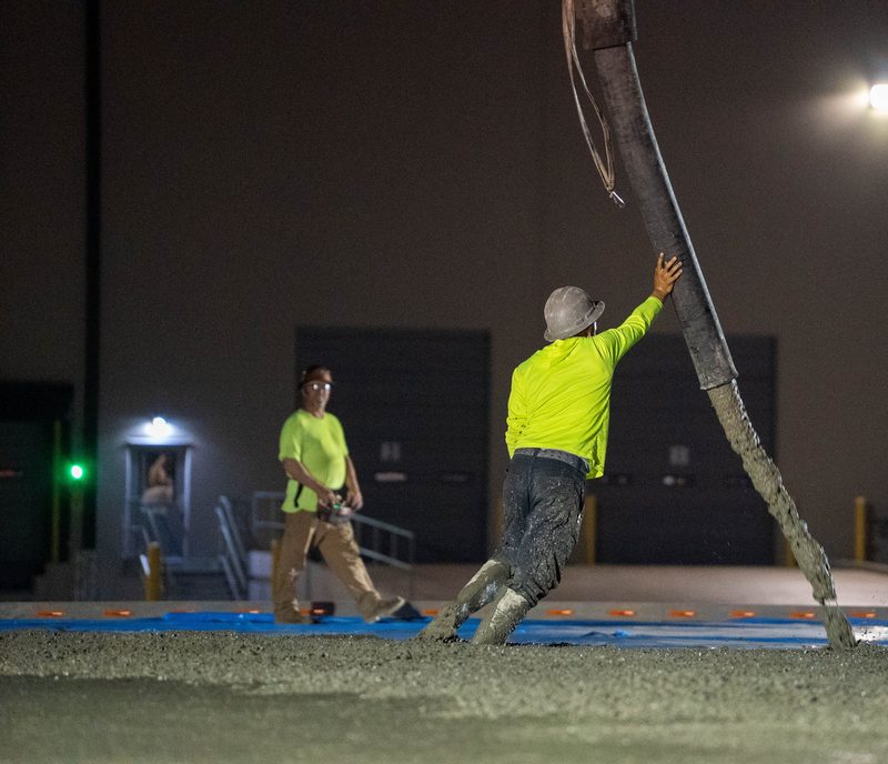 Working the pump hose on the night pour, the slab running out into the dark