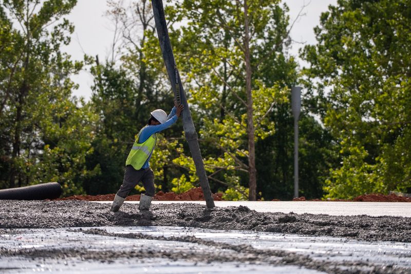 A worker walking the fresh slab out toward the treeline