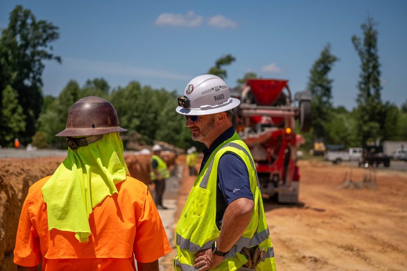 Two of the crew talking on the haul road, pump truck waiting behind
