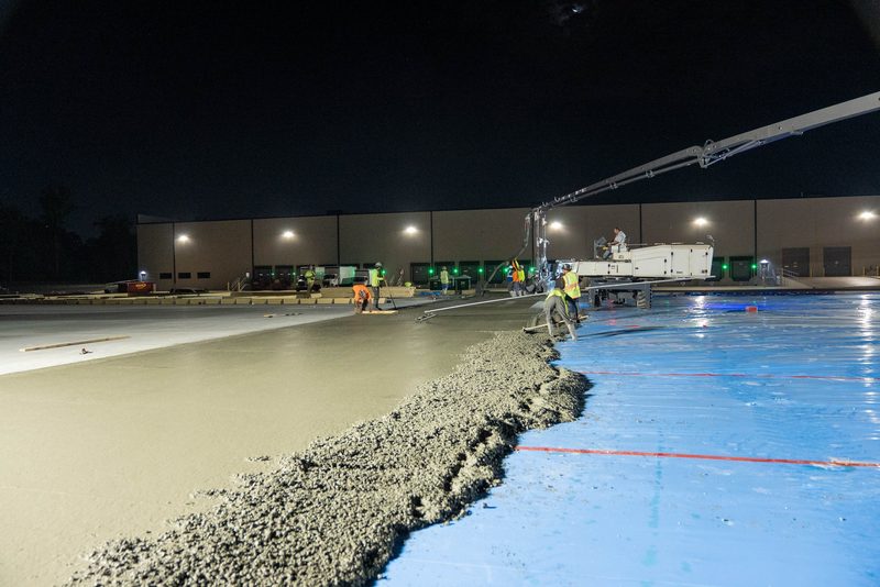 A night pour spreading across the vapour barrier, the building lit up behind