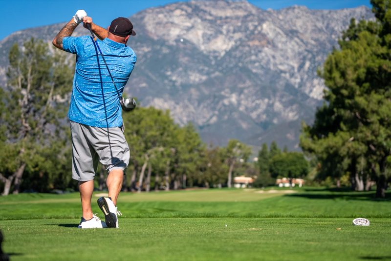 A player at the top of the backswing, the range running out to the ridge