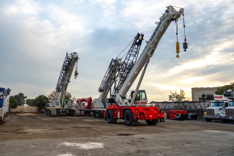 Two rough-terrain cranes parked in the yard at last light