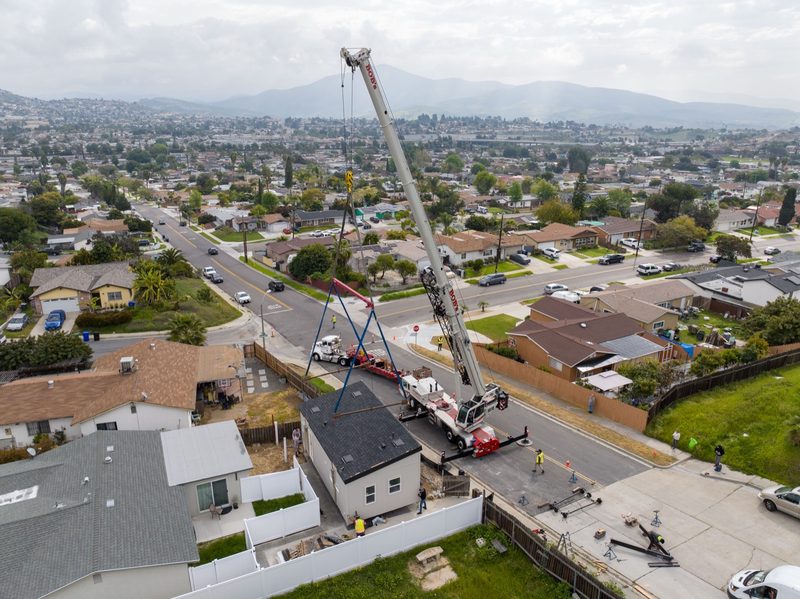 Aerial of a crane working its lift over the residential street