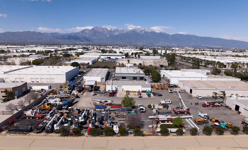 Aerial over the equipment yard, snow on the peaks behind