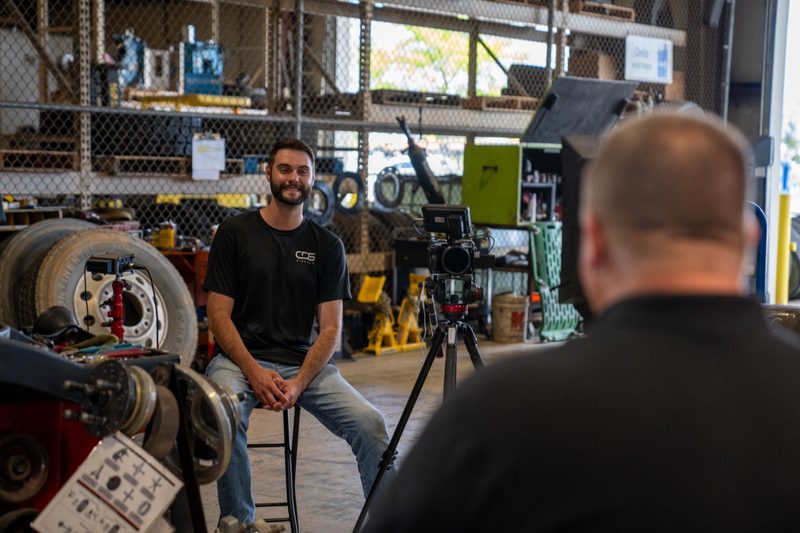 An interview under way in the shop bay, camera on the tripod between them