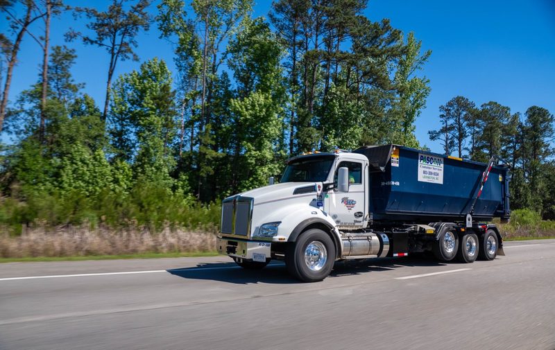 A Pascon roll-off truck running the highway with an empty container