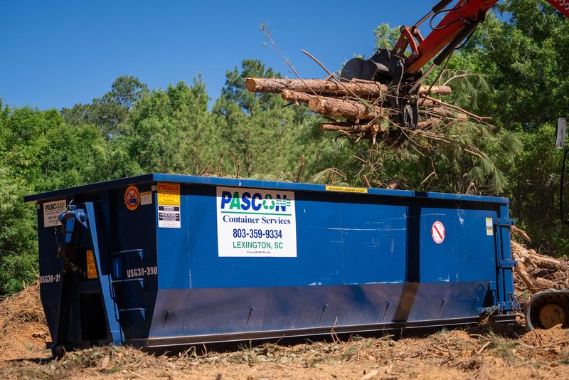 The grapple swinging a load of timber over the container