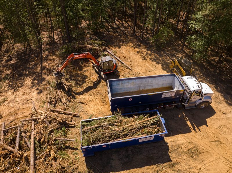 Aerial on the clearing work, containers filling with brush below