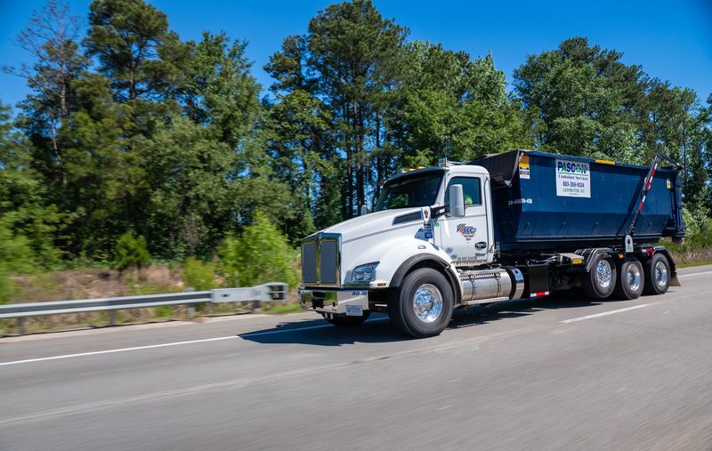 A Pascon roll-off truck running the highway with a loaded container