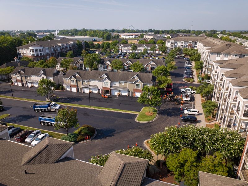 Aerial over the community, new asphalt running between the buildings