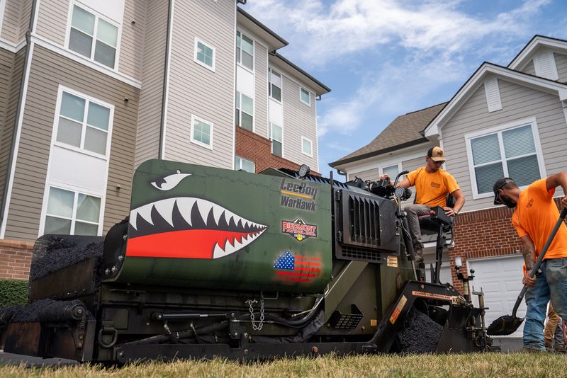 The shark-mouth LeeBoy WarHawk paver working beside the apartments