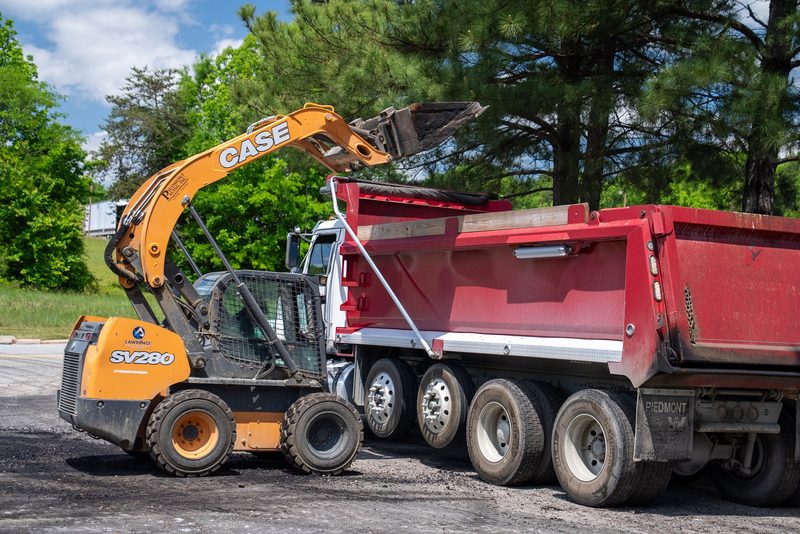 A CASE skid steer loading the dump truck at the kerb